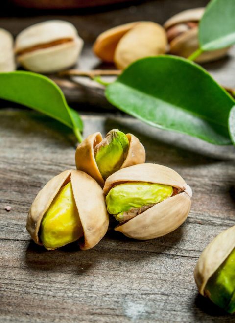 Pistachios with green leaves . On a Wooden background.